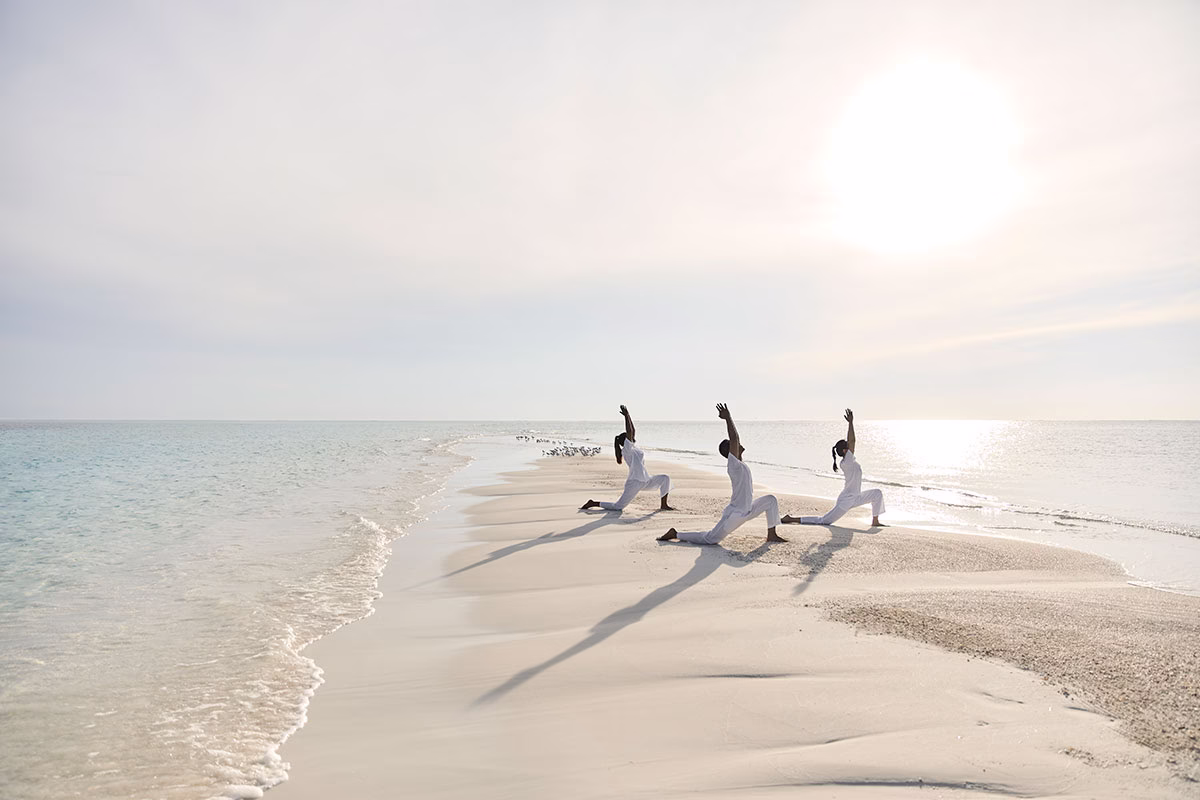 COMO Cocoa Island Gruppe macht Yoga auf einer Sandbank