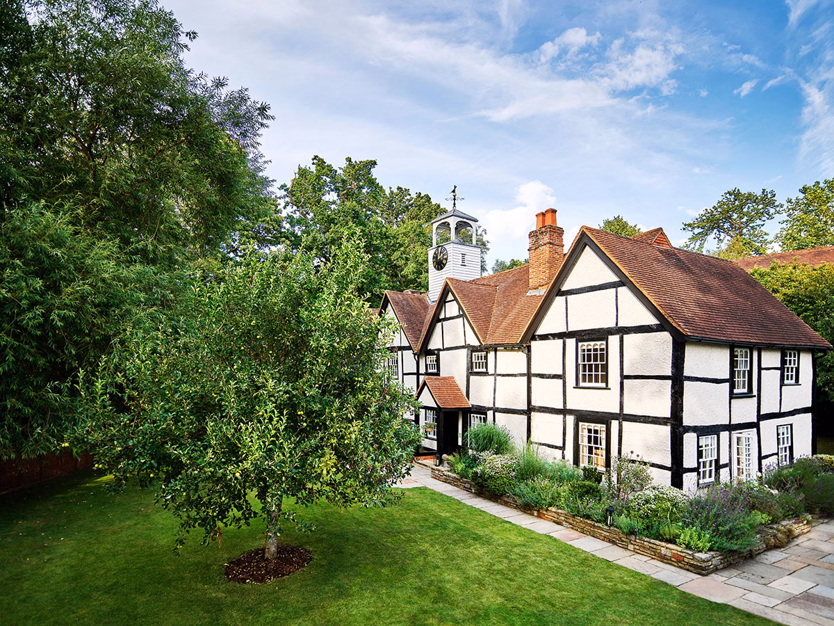 Das historische, freistehende Dower House im Coworth Park in traditioneller Fachwerkbauweise, umgeben von einem makellosen englischen Rasen und üppigen Blumenbeeten