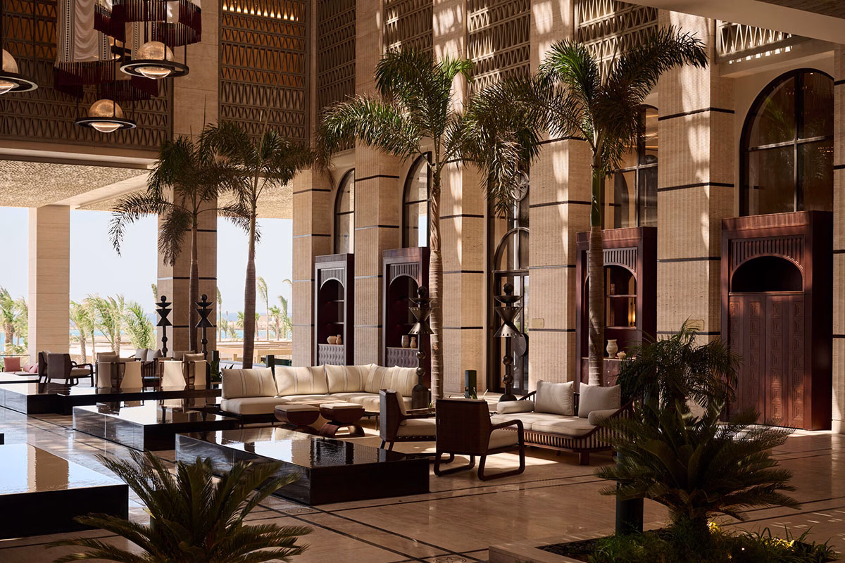Detailansicht des eleganten Loungebereichs in der Lobby des Four Seasons AMAALA mit beigen Sofas, dunklen Holzelementen und hohen Säulen im Spiel von Licht und Schatten