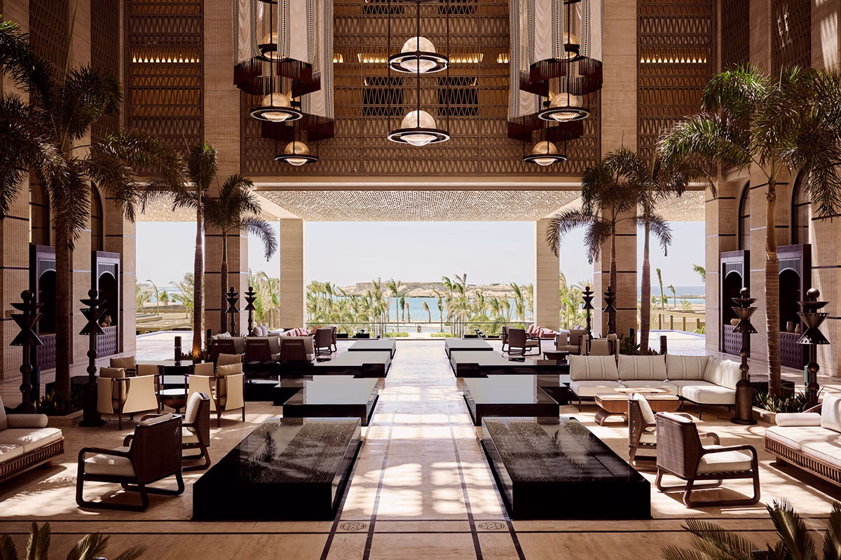 Luxuriöse, lichtdurchflutete Hotel-Lobby im Four Seasons AMAALA mit hohen Decken, monumentalen Hängeleuchten, Palmen und stilvollen Sitzecken, die den Blick auf das Meer freigeben