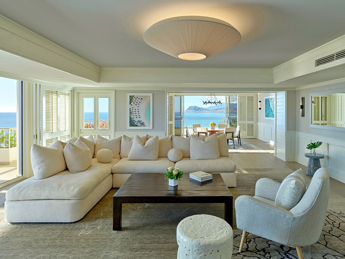 Das lichtdurchflutete, großzügige Wohnzimmer einer Luxus-Suite im Four Seasons Oahu mit einer hellen Sofalandschaft und großen Fensterfronten, die den Blick auf den Pazifik freigeben