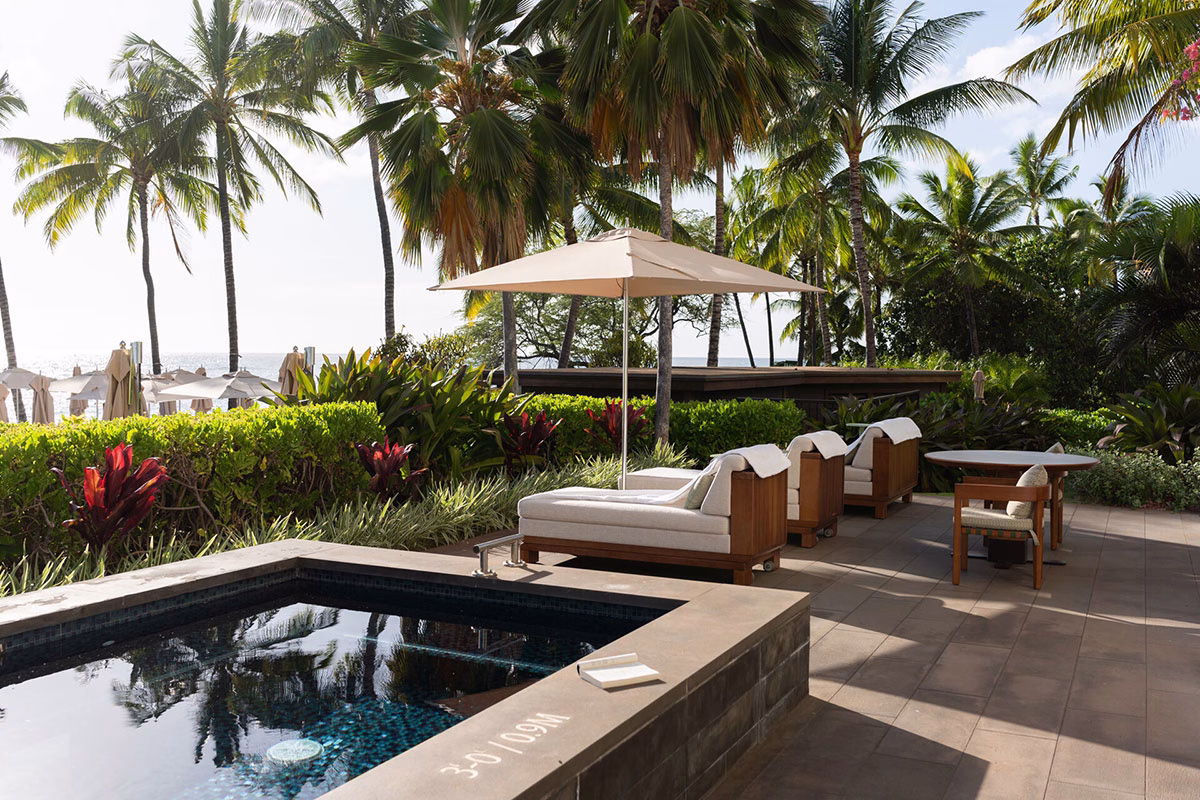 Private, von Palmen umgebene Erdgeschoss-Terrasse einer Suite im Four Seasons Oahu mit bequemen Sonnenliegen, einem Sonnenschirm und einem exklusiven, kleinen Whirlpool