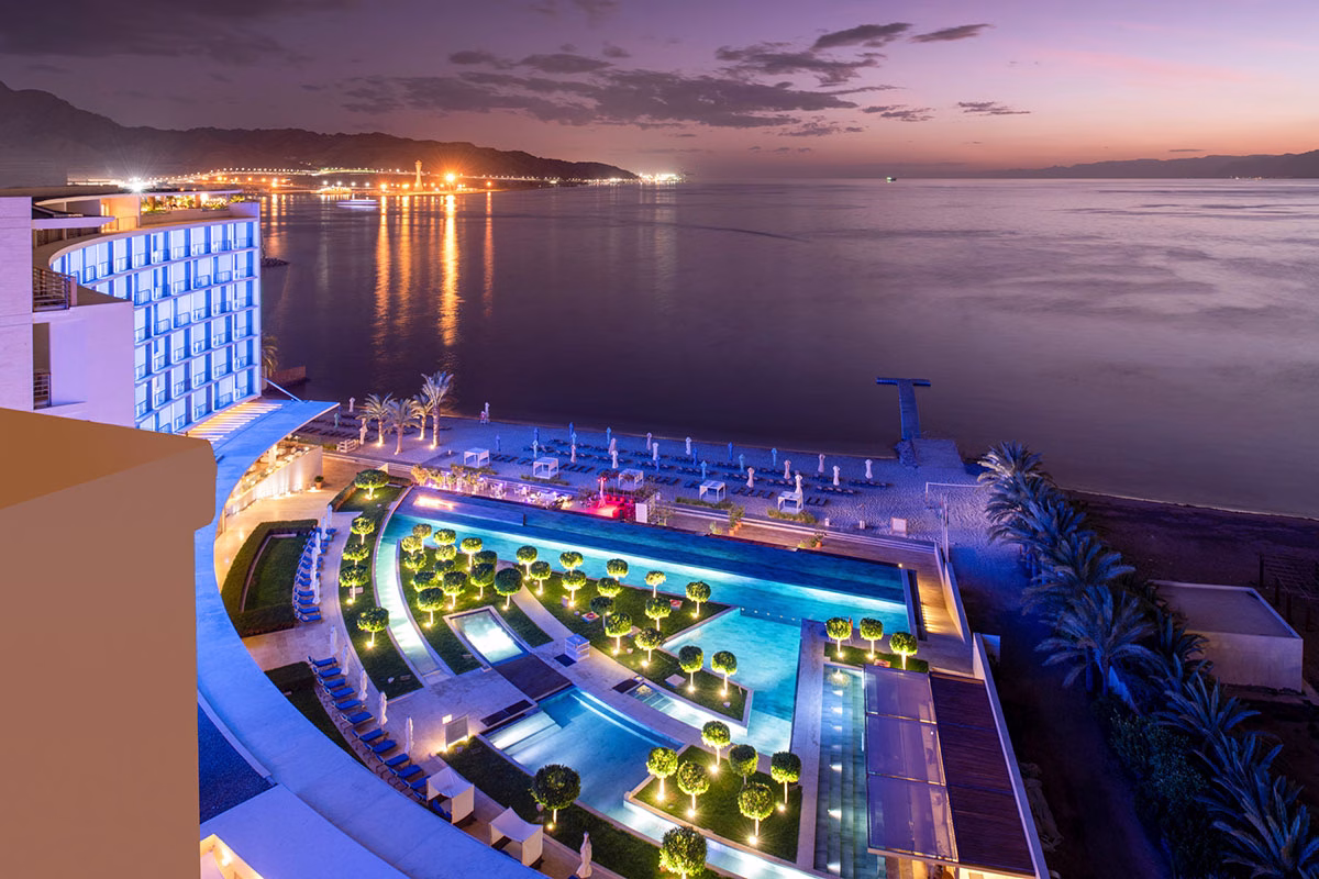 Blick auf den in der Nacht beleuchteten Pool des Kempinski Hotel Aqaba Red Sea neben dem Strand