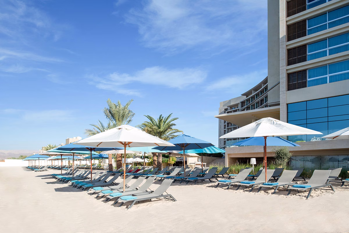 Sandstrand mit Liegen und Sonnenschirmen am Kempinski Hotel Aqaba Red Sea