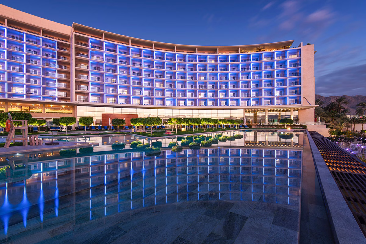 Gebäude des Kempinski Hotel Aqaba Red Sea mit Pool in der Nacht