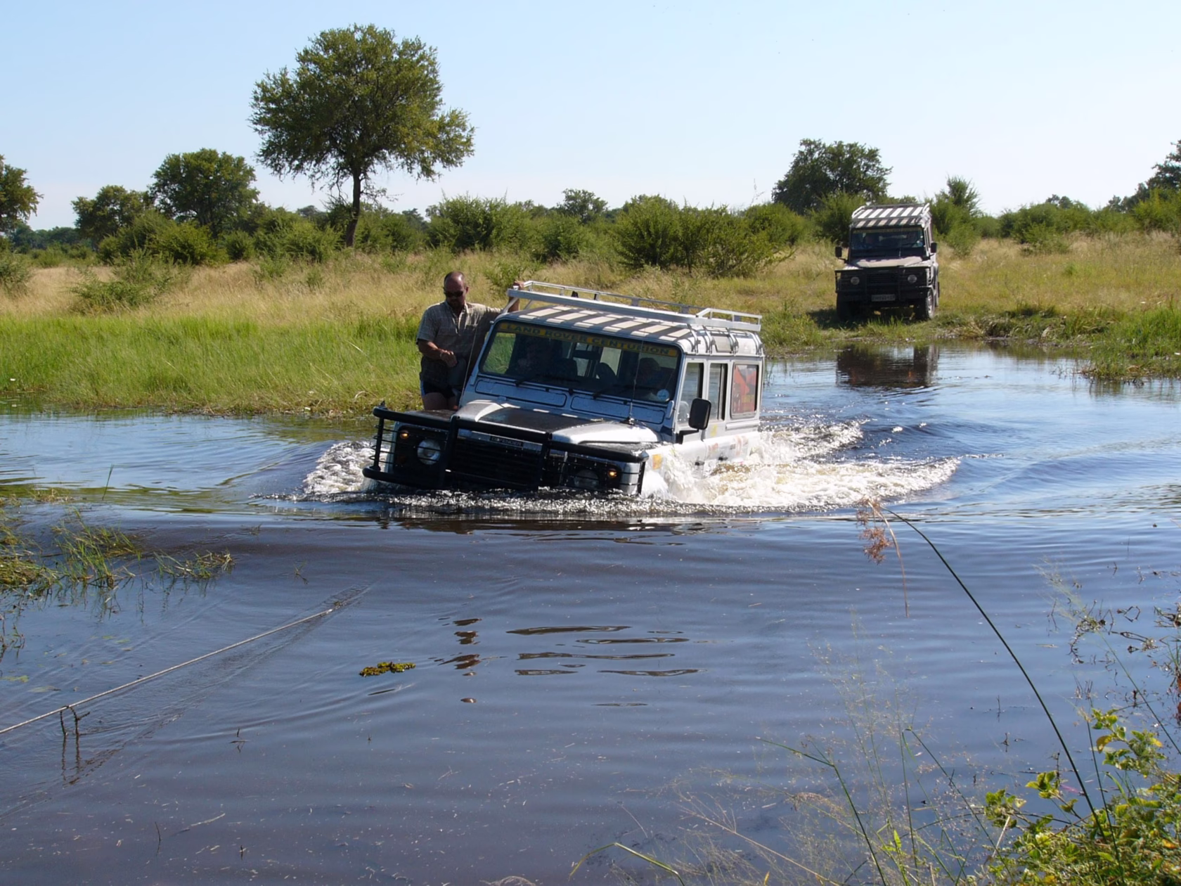 Zwei Jeeps fahren durchs Wasser im Okavango-Delta