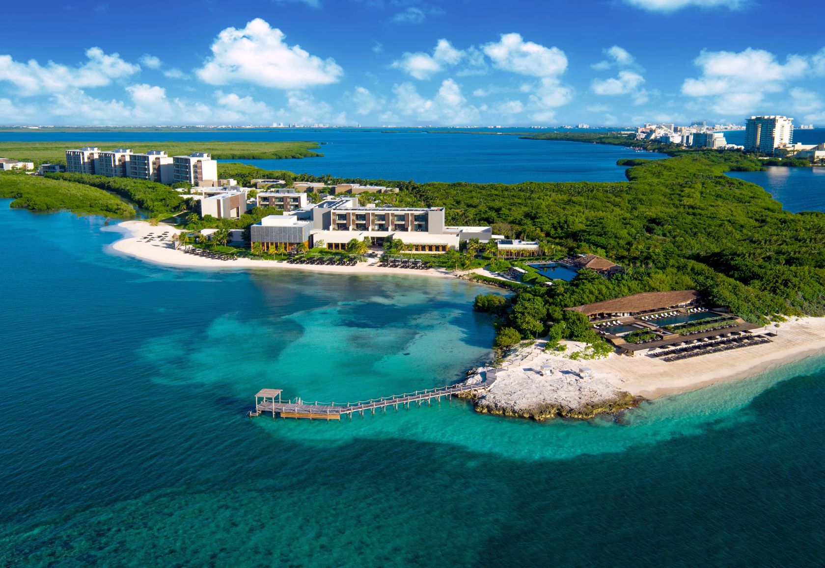 Luftaufnahme des luxuriösen NIZUC Resort & Spa an der Riviera Maya, eingebettet in üppige grüne Mangroven, mit weißen Sandstränden, einem privaten Holzsteg und Blick auf das kristallklare, türkisfarbene Karibische Meer