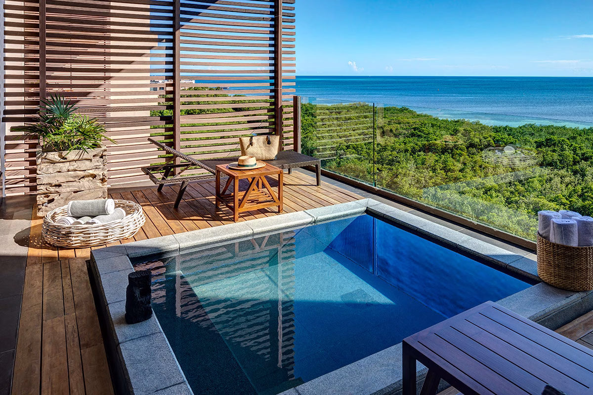 Privater Balkon im NIZUC Resort & Spa mit einem eingelassenen, quadratischen Whirlpool, einer hölzernen Sonnenterrasse mit Liege und einem atemberaubenden Blick über dichte grüne Mangrovenwälder bis hin zum offenen Ozean