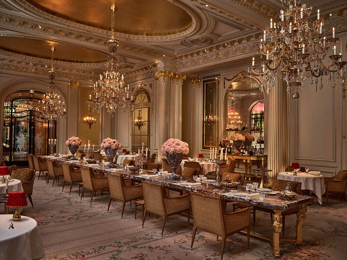 Der majestätische Speiseraum des Spitzenrestaurants von Jean Imbert mit einer vergoldeten Kuppeldecke, riesigen Kristallkronleuchtern und einer monumentalen, zentralen Festtafel aus edlem Marmor