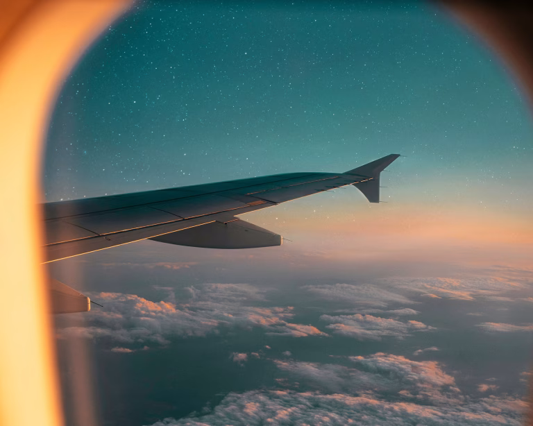 Flugzeugflügel über den Wolken mit Sternenhimmel und warmem Licht