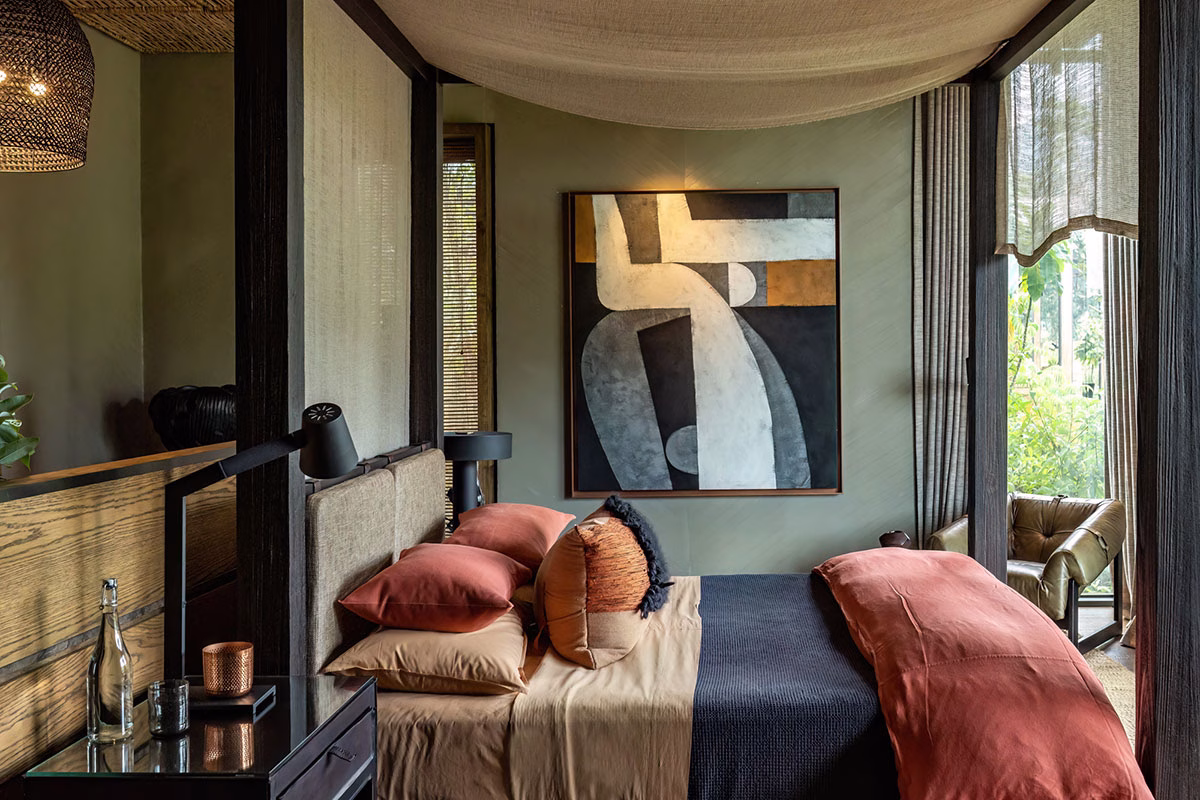 Luxuriöses Schlafzimmer im Singita Kataza House mit einem eleganten Himmelbett, warmen Terrrakotta-Kissen, einem großen abstrakten Gemälde an der Wand und stilvollem, afrikanisch inspiriertem Design