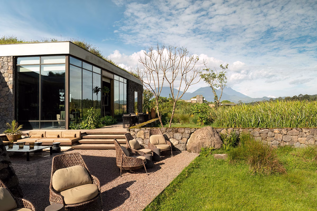 Großzügige Außenterrasse der Singita Kwitonda Lodge mit komfortablen Flechtsesseln, einer modernen Lounge-Ecke und freiem Blick auf die umliegende vulkanische Berglandschaft