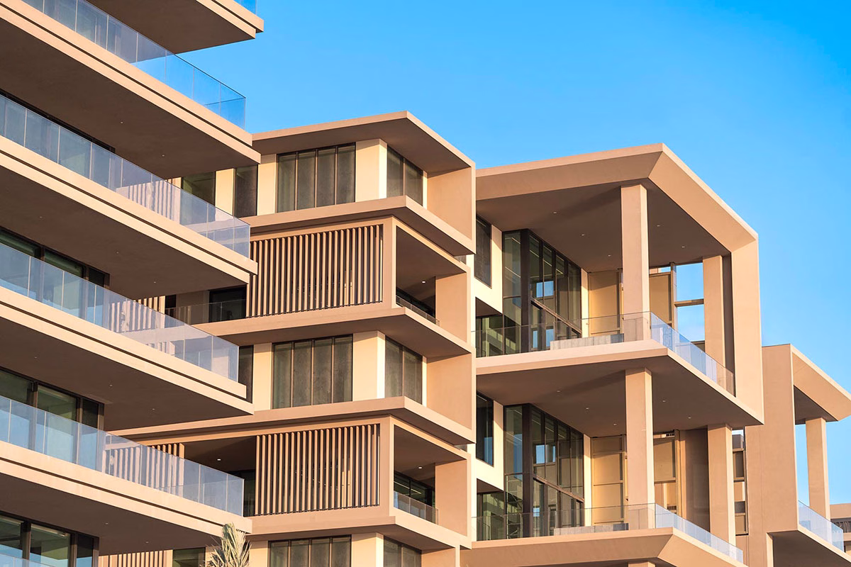 Nahaufnahme der modernen Fassade des Six Senses The Palm mit architektonischen Details, gestapelten Balkonen mit Glasgeländern und warmen, erdigen Farbtönen