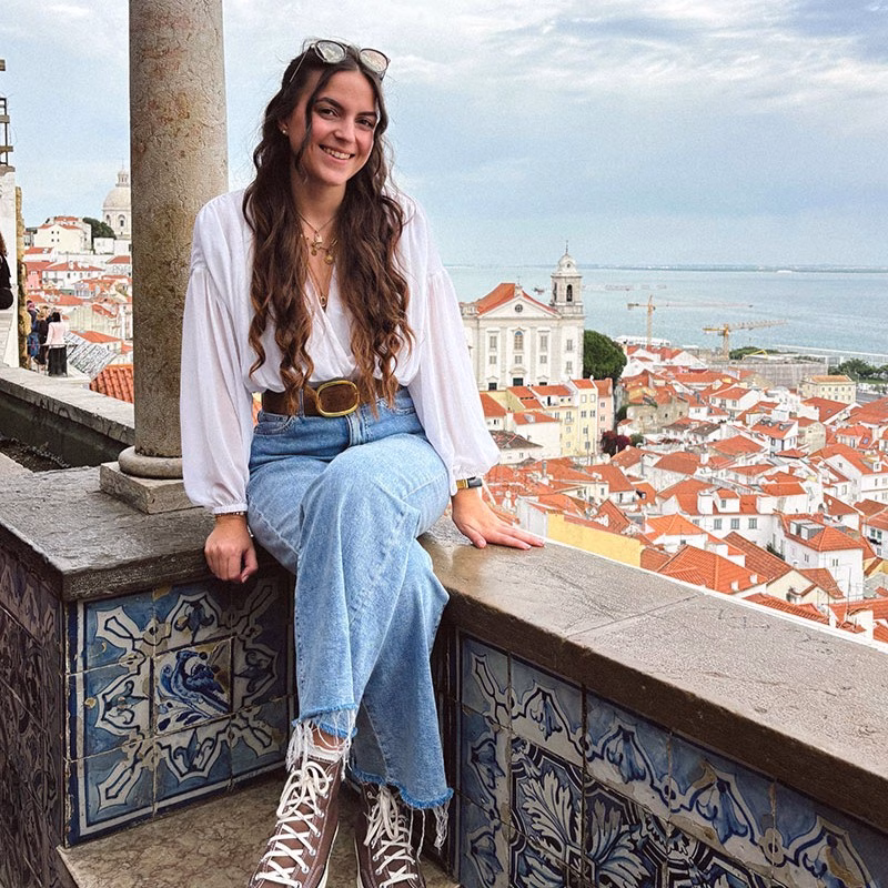 Tessa in Lissabon auf einer Mauer sitzend