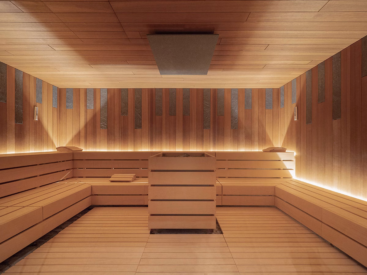 Großzügige, modern gestaltete finnische Sauna im The Chedi Andermatt, komplett aus hellem Holz gefertigt mit mehrstufigen Sitzbänken und einer indirekten, warmen LED-Beleuchtung