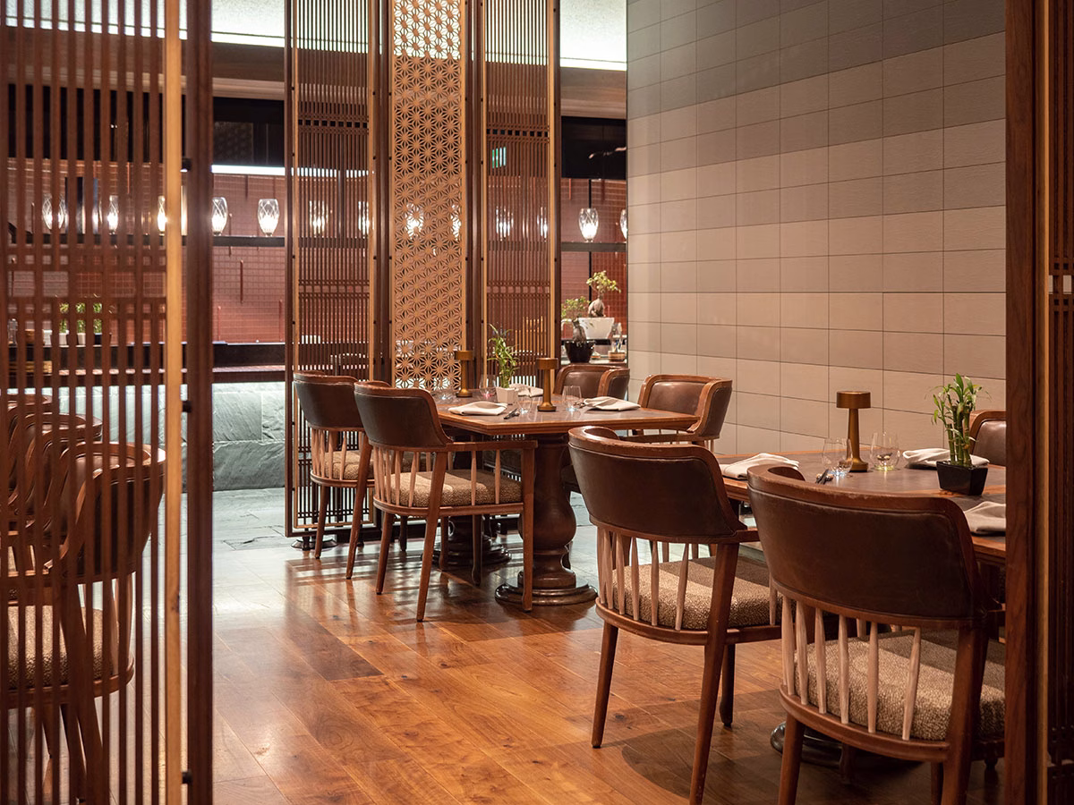 Stilvolles asiatisches Ambiente im „The Japanese Restaurant“ im The Chedi Andermatt mit feinen Holzstühlen und filigranen, gemusterten Holz-Raumteilern, die Privatsphäre zwischen den Tischen schaffen