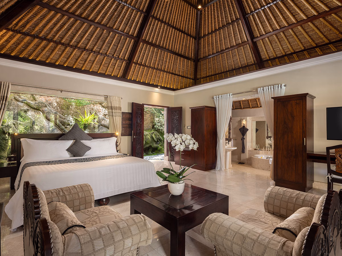 Das geräumige Schlafzimmer der Elephant Villa im Viceroy Bali, ausgestattet mit einem Kingsize-Bett, gemütlichen Sesseln im Kolonialstil und freiem Blick auf das Badezimmer sowie den angrenzenden Außenbereich