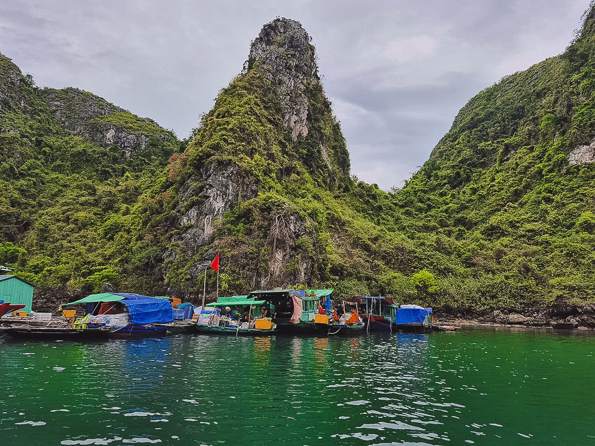 Floating Village mit bunten Booten vor beeindruckender Kulisse der Kalksteinfelsen