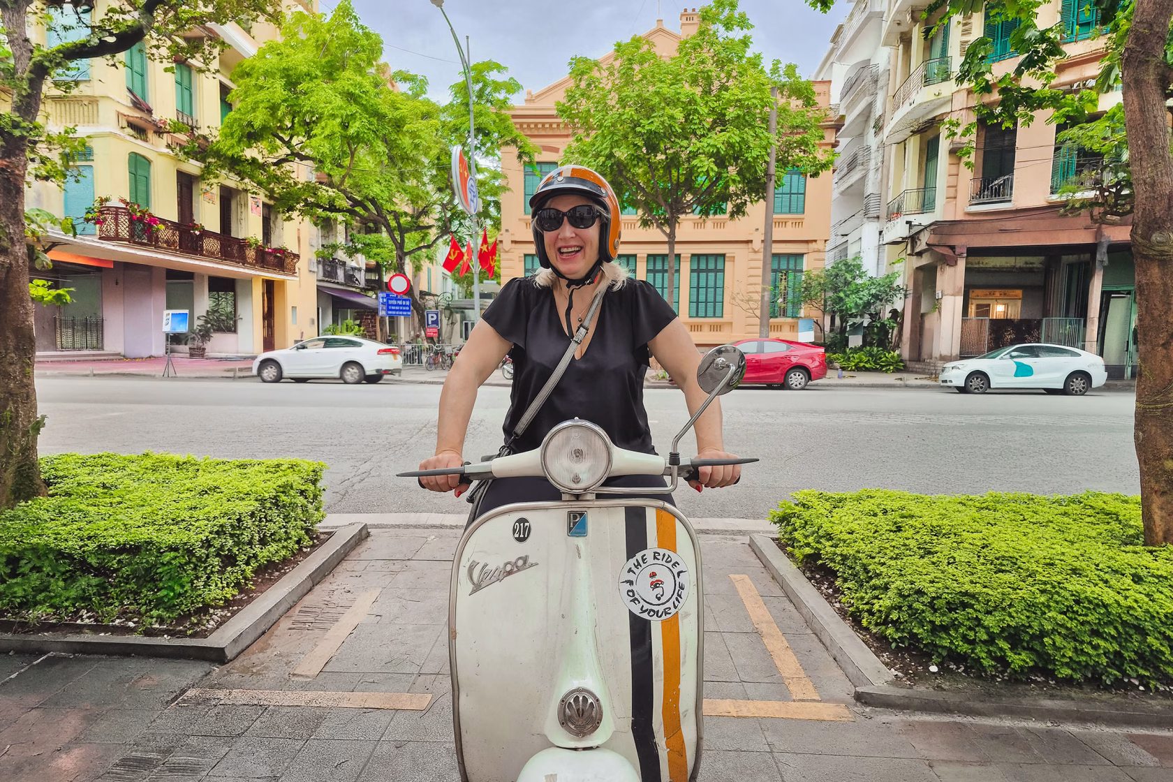 Vietnam sitzt auf einer Vintage Vespa, Hanoi im Hintergrund