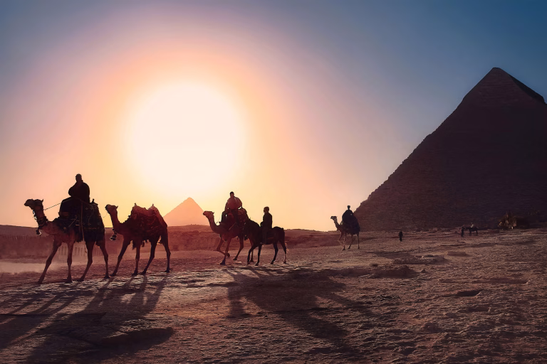 Menschen auf Kamelen bei Sonnenuntergang in Ägypten vor einer Pyramide