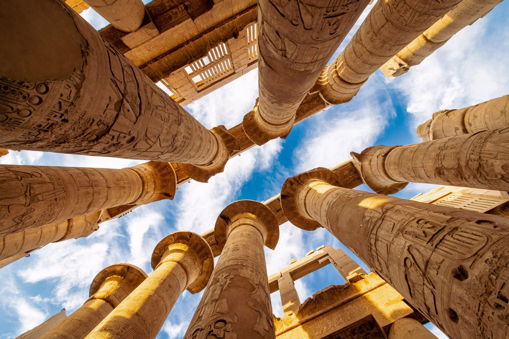 Monument in Ägypten von unten in den Himmel fotografiert, gesäumt mit antiken Säulen aus Sandstein