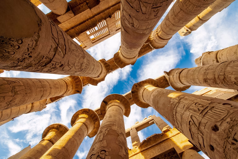 Monument in Ägypten von unten in den Himmel fotografiert, gesäumt mit antiken Säulen aus Sandstein