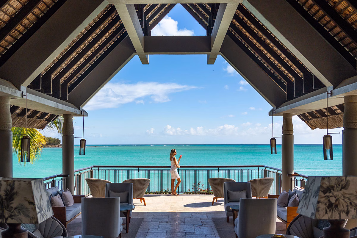 Frau steht auf Balkon am Meer im Royal Palm Beachcomber Luxury