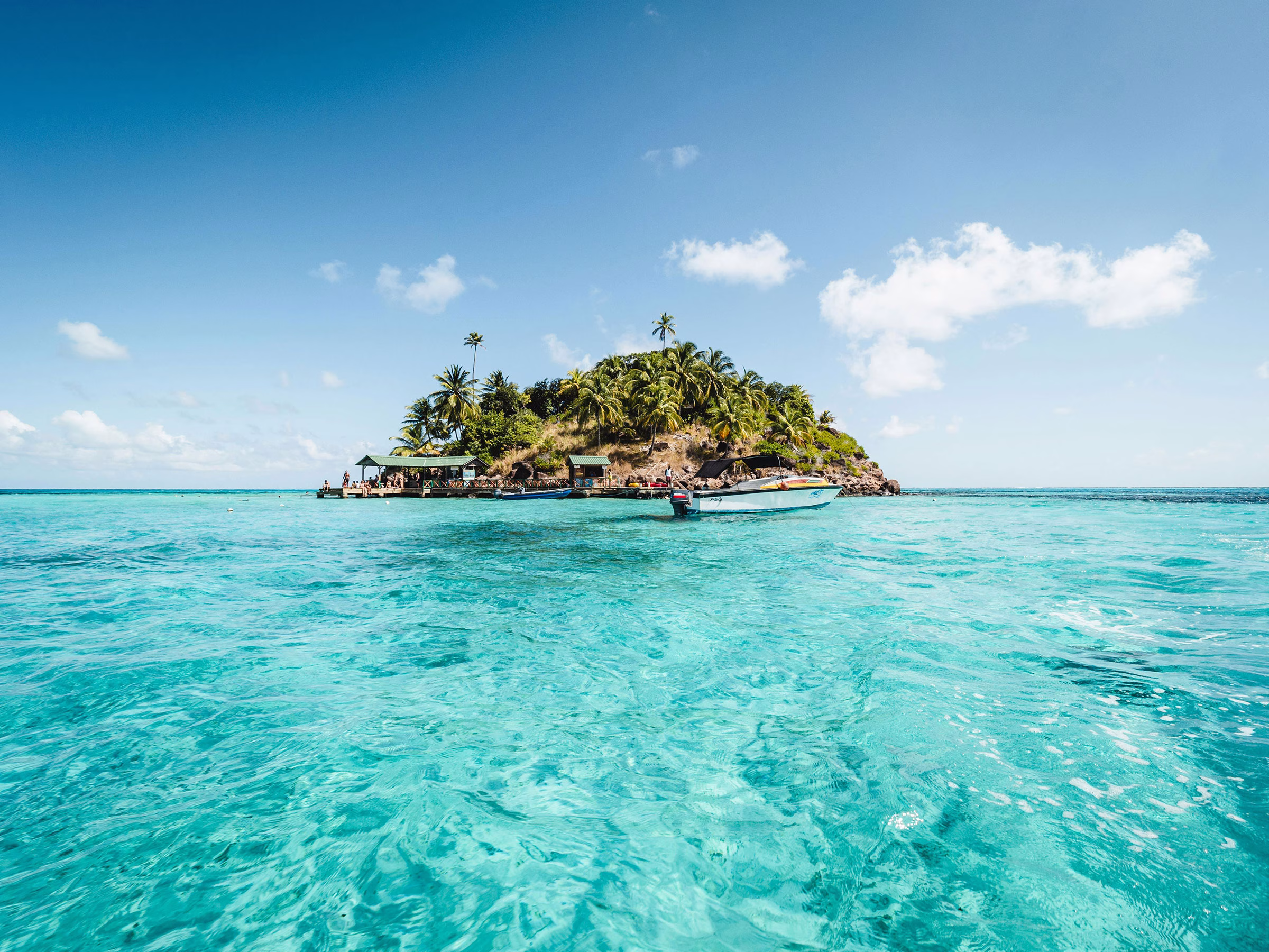 Türkisfarbenes Meer mit Aussicht auf eine kleine Insel umgeben von üppiger Natur