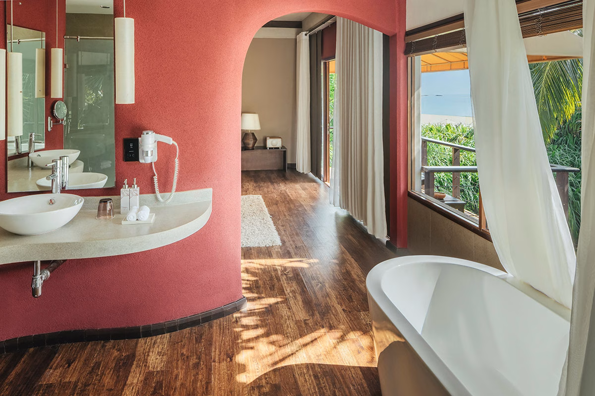 Badezimmer mit Badewanne und Waschbecken umgeben von Pflanzen und Bäumen auf der Terrasse